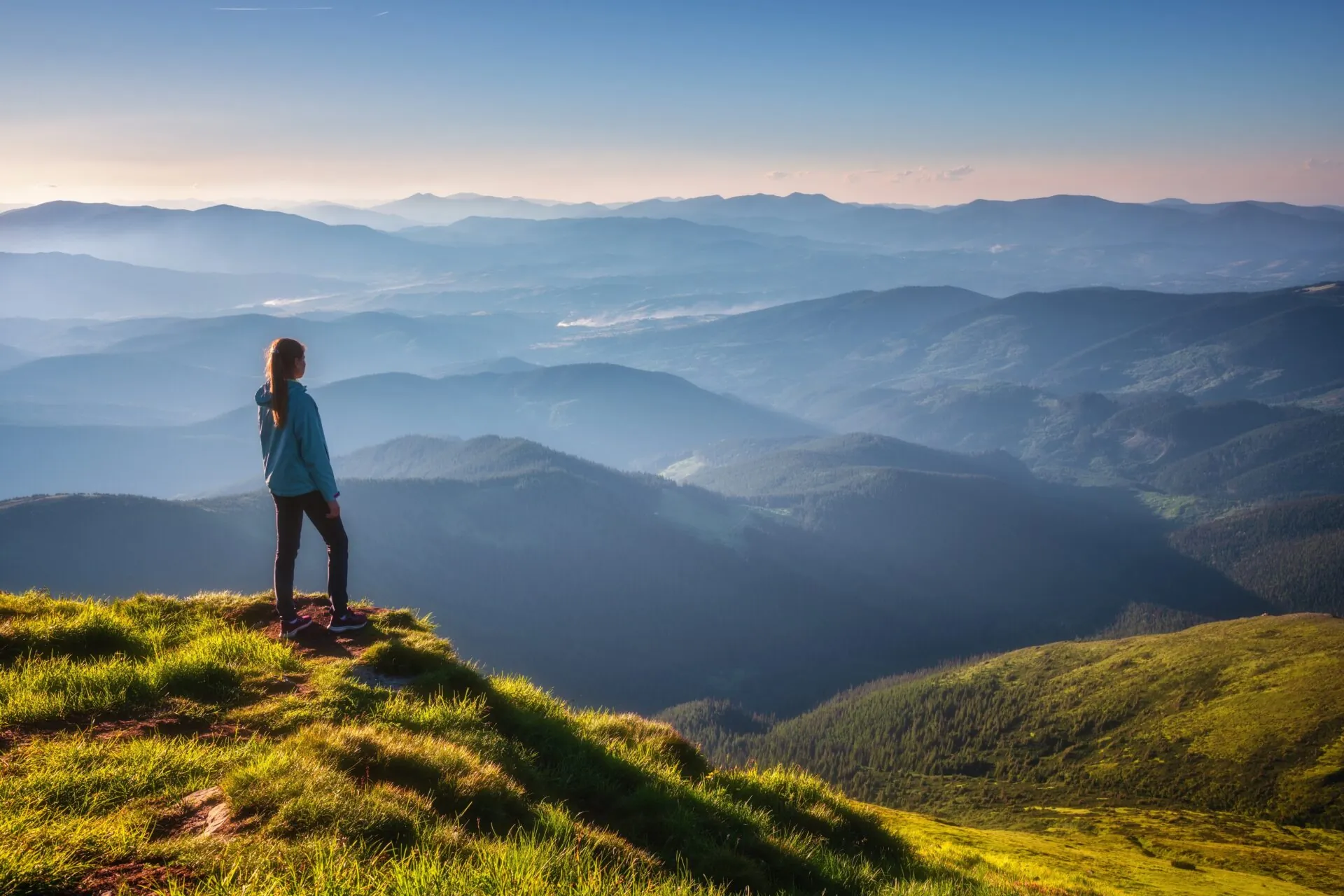 Girl,On,Mountain,Peak,With,Green,Grass,Looking,At,Beautiful